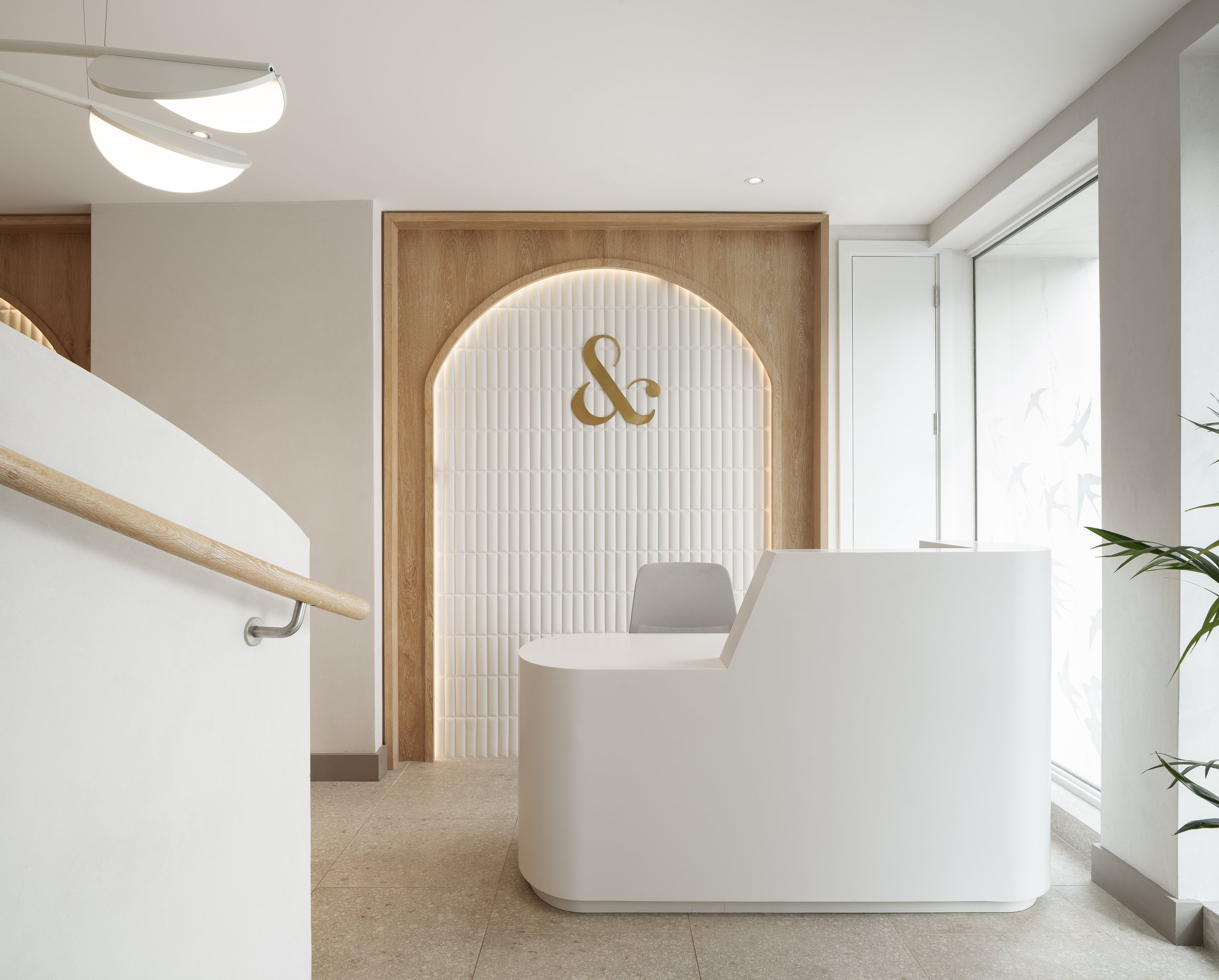 A white curved reception desk under an arched alcove, with fluted panelling and a pendant light.